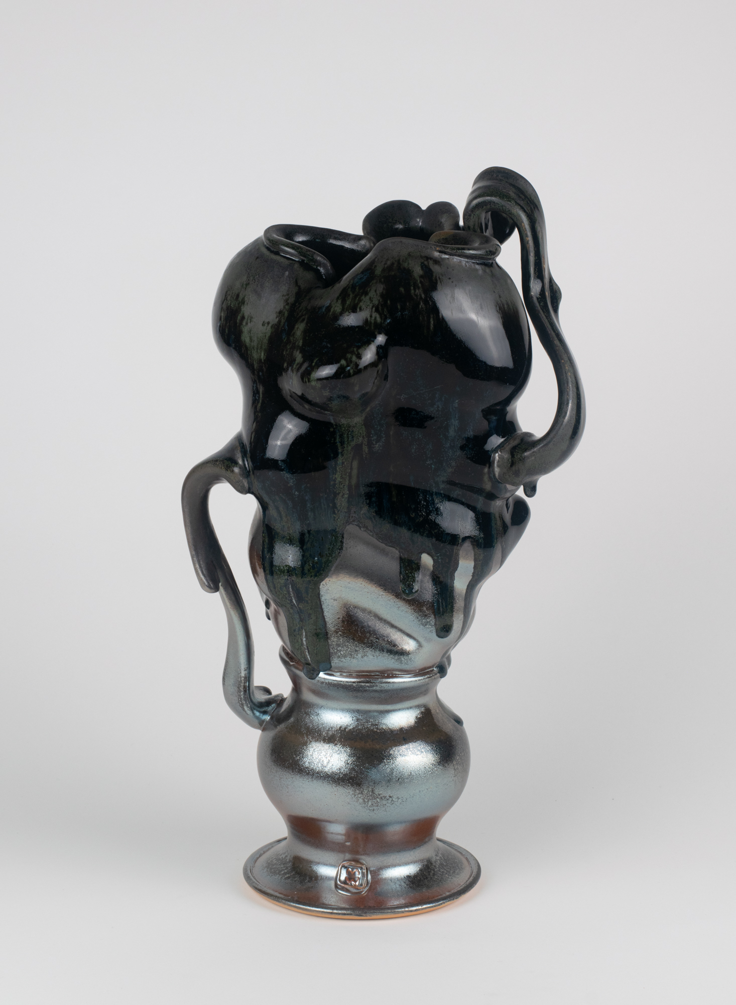 Abstract ceramic vase with a glossy black top and metallic silver base featuring flowing organic shapes